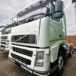 Volvo FM 400 6x4 truck tractor in white with slight green tint, stone guard fitted, side view in dealership lot