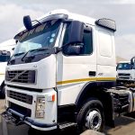 White Volvo FM 400 6x4 horse with black-and-white striped sunvisor, 400 badge visible, side profile